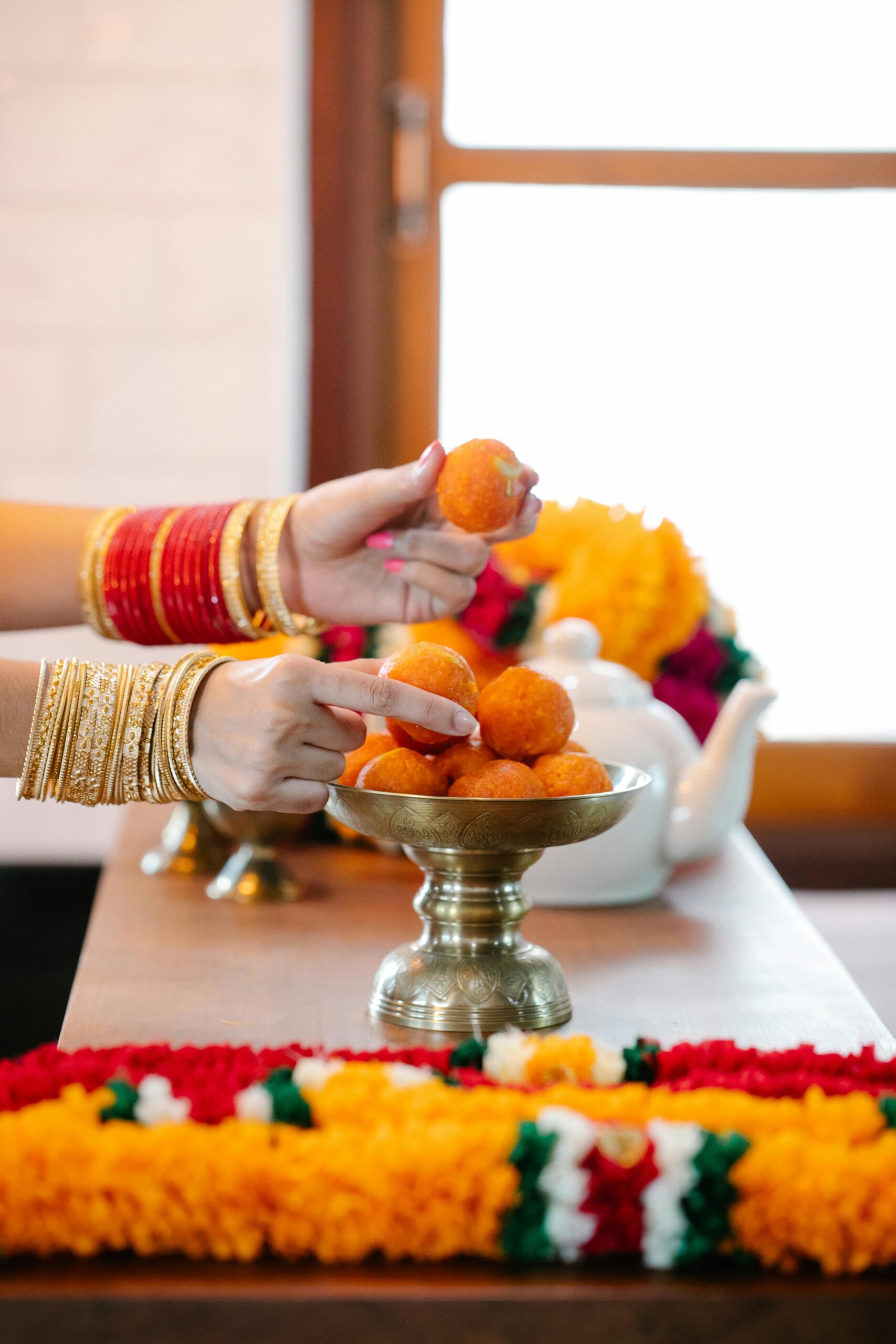 A vibrant display of Indian sweets being served during a festive occasion, showcasing cultural jewelry and decoration.